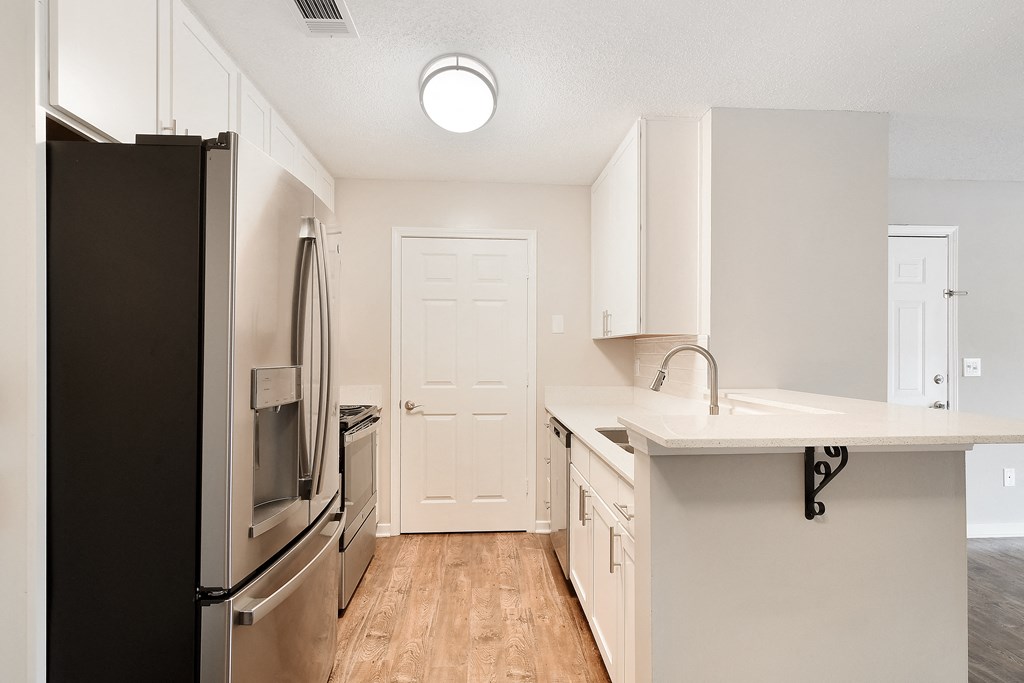 an empty kitchen with stainless steel appliances and a white counter top at The Woodlands Apartment Homes, Meridian, MS