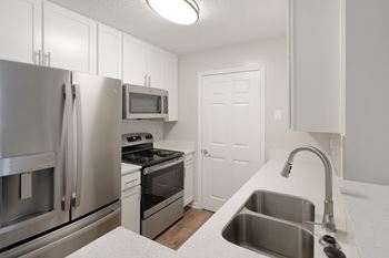 a kitchen with stainless steel appliances and white cabinets at The Woodlands Apartment Homes, Meridian, MS, 39301