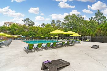a swimming pool with green and yellow chairs and umbrellas at Charleston Apartment Homes, Alabama