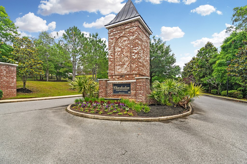the roundabout in front of a brick tower with a sign on it at Charleston Apartment Homes, Mobile, Alabama
