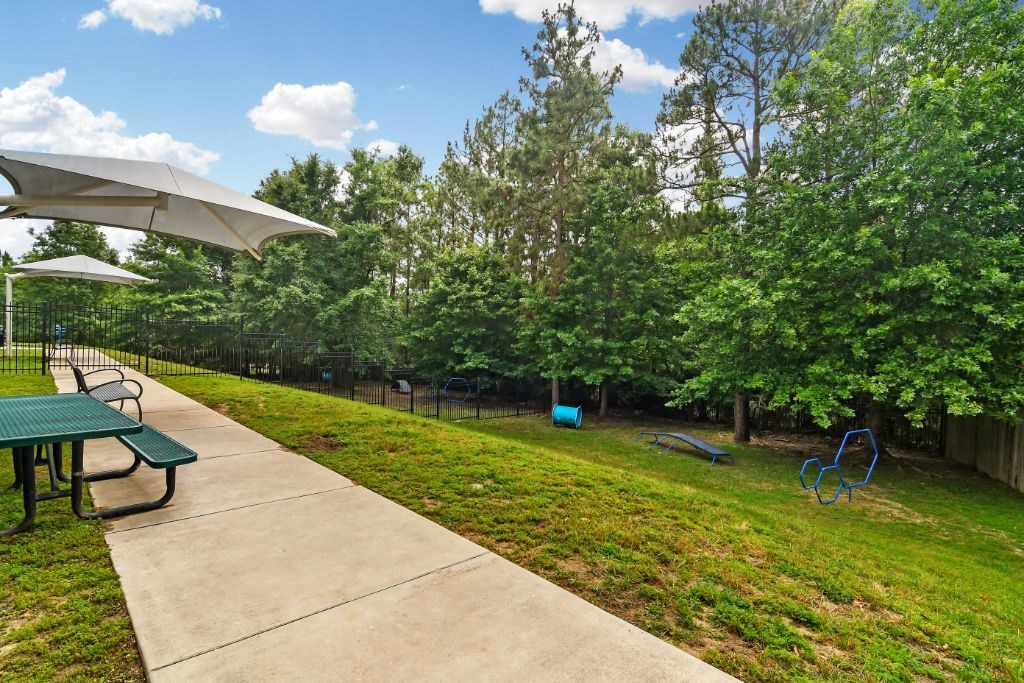 a picnic area with umbrellas and benches in a grassy area with trees