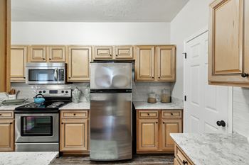 a kitchen with stainless steel appliances and wooden cabinets at Charleston Apartment Homes, Mobile, 36695