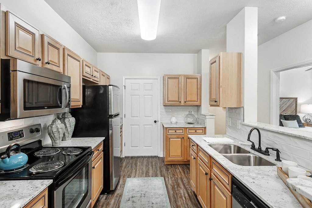 a kitchen with wooden cabinets and black appliances at Charleston Apartment Homes, Mobile, AL