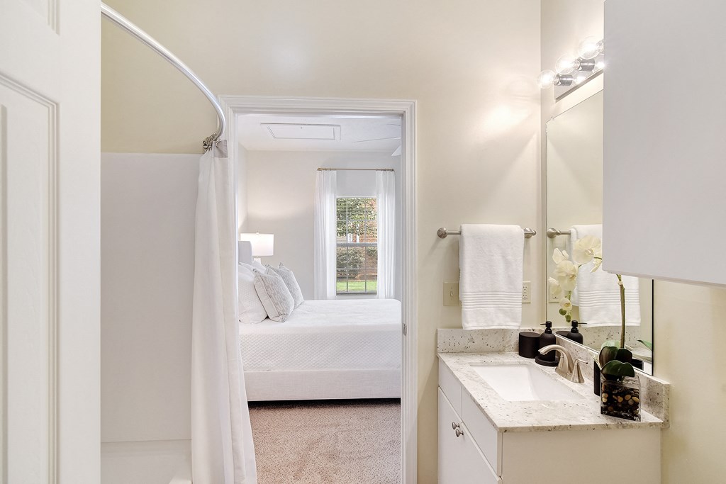 a bathroom with a sink and a mirror and a bedroom with a bed at Summit of Shreveport Apartments, Shreveport, LA, 71105