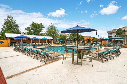 a swimming pool with chaise lounge chairs and umbrellas
