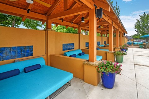 a row of cabanas with blue couches and potted plants
