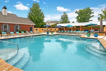 A large outdoor swimming pool with a sun lounger and umbrellas at Summit of Shreveport Apartments, Shreveport, 71105