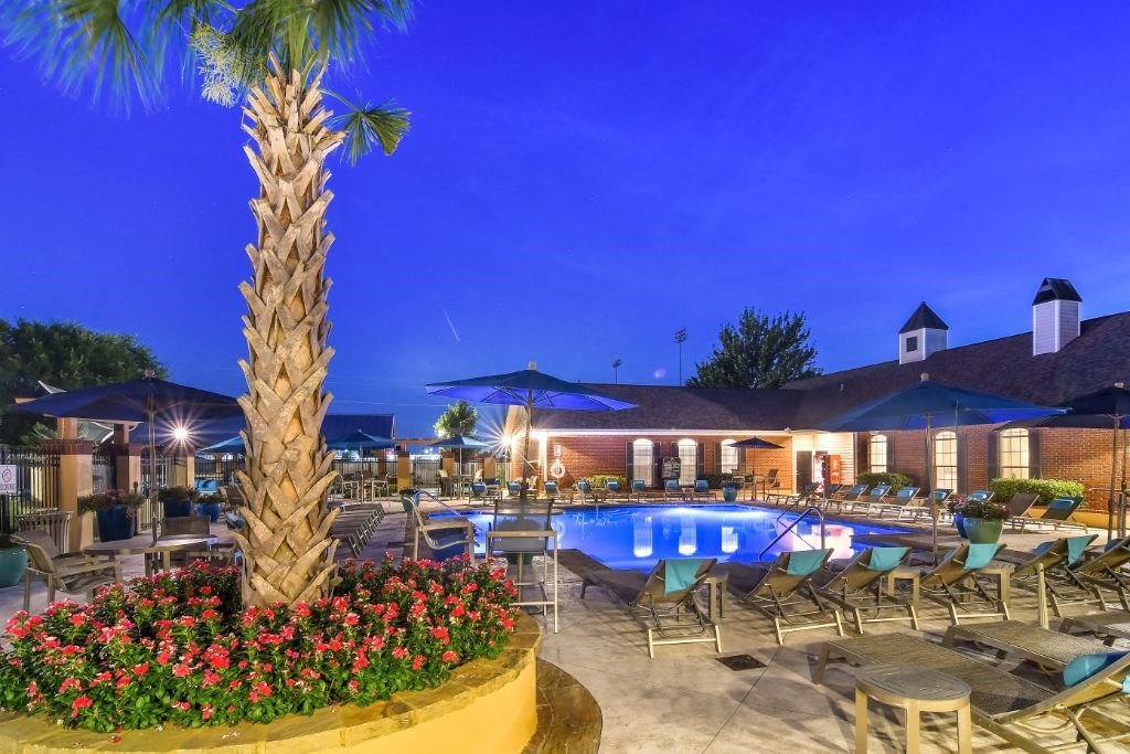 a resort style pool with lounge chairs and umbrellas at night at Summit of Shreveport Apartment Homes, Shreveport, LA