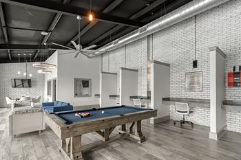 a pool table in a living room with white brick walls at Parkwest Apartment Homes, Hattiesburg, MS