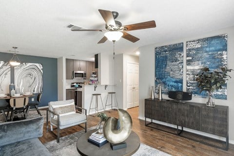 a living room with a ceiling fan and a kitchen in the background  at Parkwest Apartment Homes, Hattiesburg
