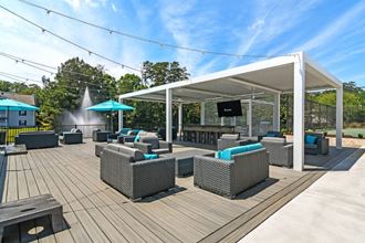 a patio with wicker couches and chairs and a flat screen tv - Photo Gallery