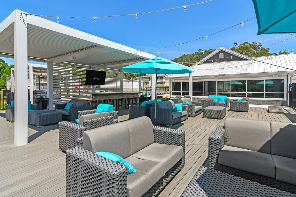 a roof top patio with chairs and umbrellas and a tv at The Woodlands Apartment Homes, Meridian, MS