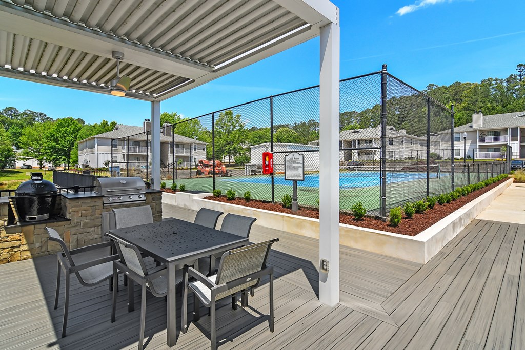 a covered patio with a table and chairs next to a pool at The Woodlands Apartment Homes, Mississippi 39301