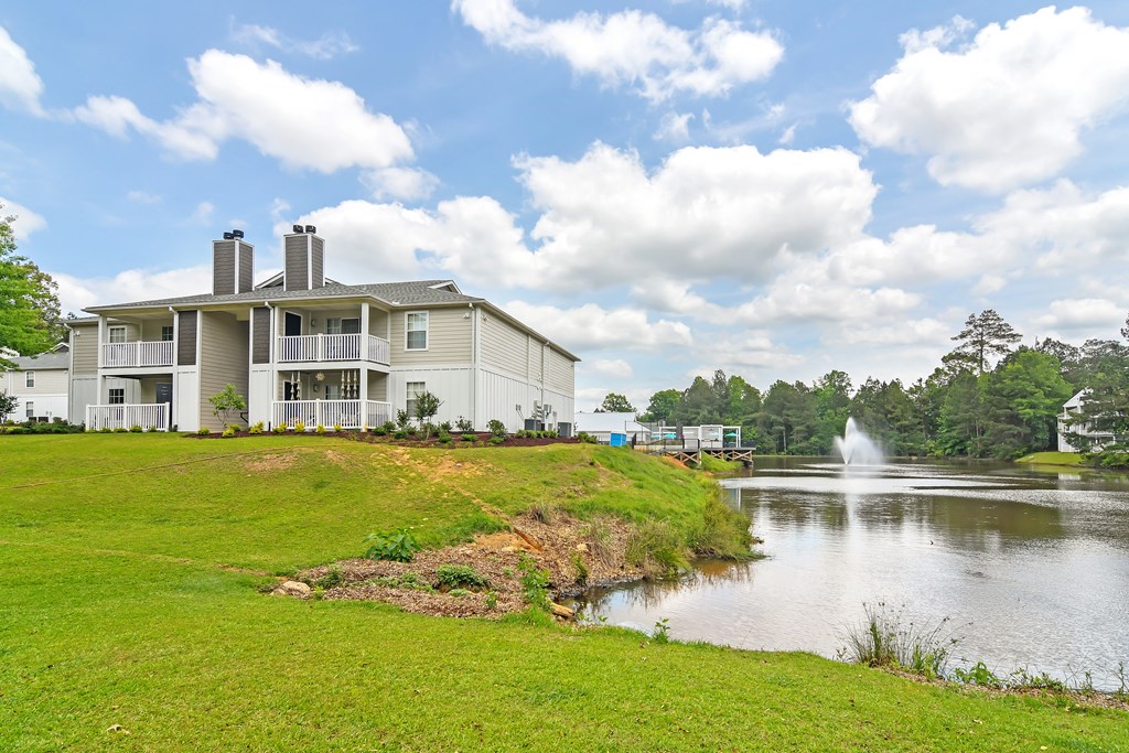 the view of a building next to a lake with a fountain at The Woodlands Apartment Homes, Meridian