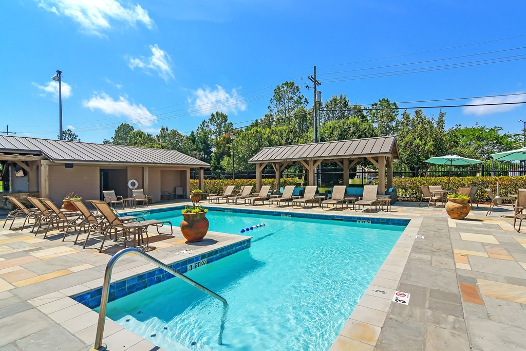 our resort style swimming pool is filled with lounge chairs and umbrellas at Highpointe Apartment Homes, Mississippi