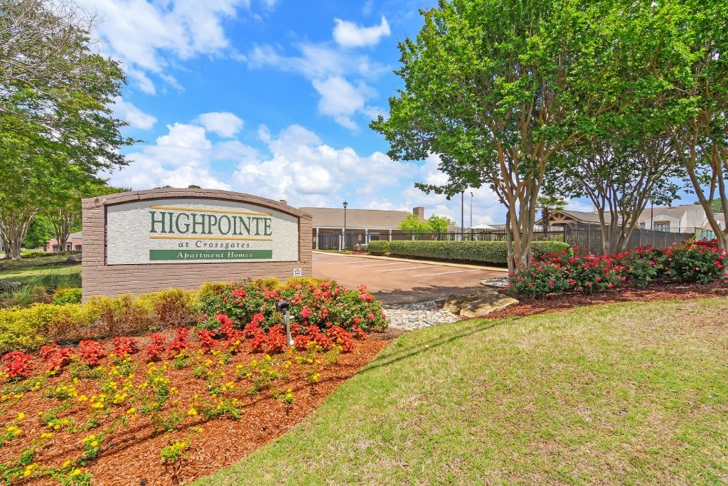 a building with a sign that says high pointe in front of a park with trees and  at Highpointe Apartment Homes, Brandon, MS, 39042