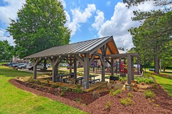 A pavilion with a metal roof and wooden pillars is surrounded by a garden with a variety of plants and flowers at Highpointe Apartment Homes, Brandon, 39042