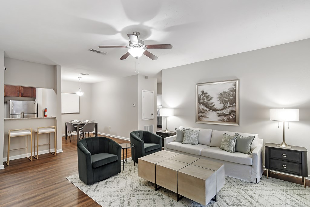 Open living room with a couch and chairs and a ceiling fan at Highpointe Apartment Homes, Brandon, Mississippi