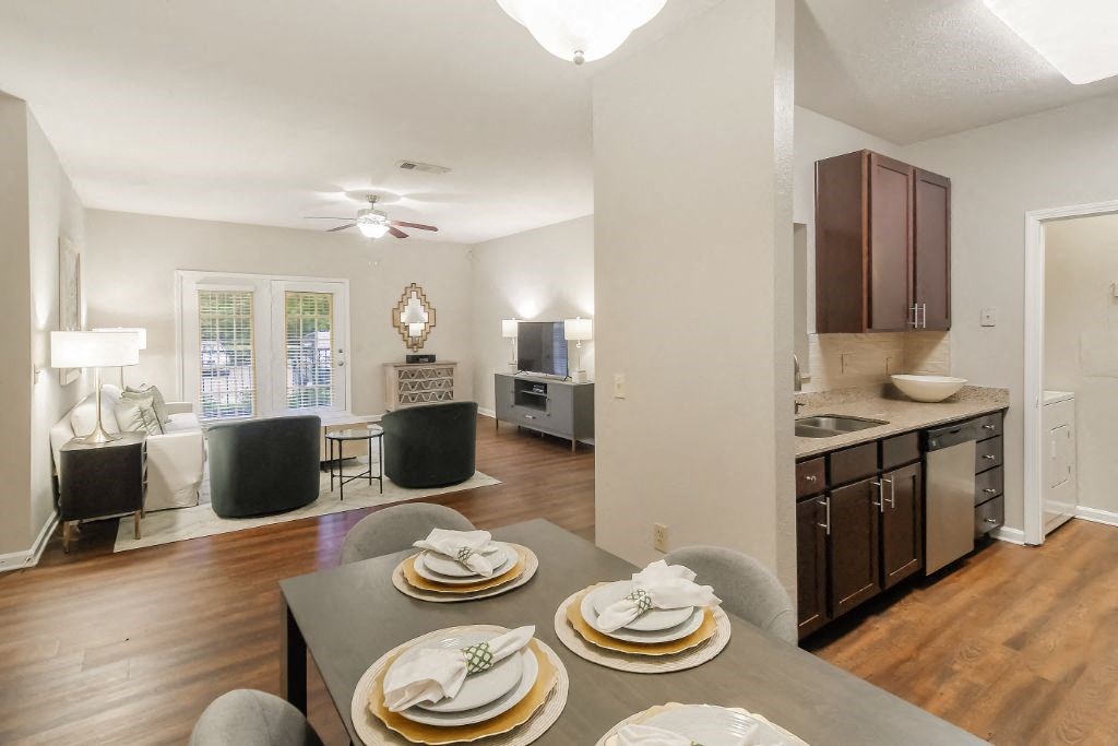 a dining room with a table and chairs and a kitchen in the background  at Highpointe Apartment Homes, Brandon, 39042