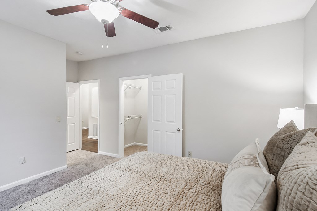 Bedroom with a large bed and a ceiling fan at Highpointe Apartment Homes, Brandon, MS, Mississippi