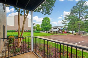 A view from a balcony looking out at a parking lot and trees at Highpointe Apartment Homes, Mississippi  , 39042