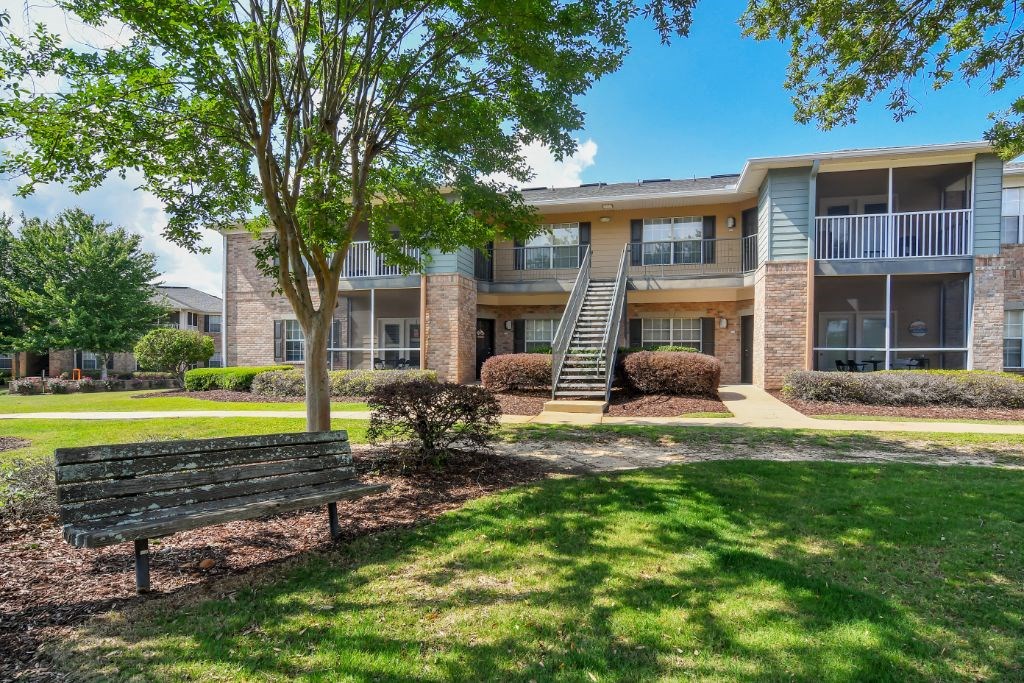 a park bench in front of an apartment building at Ashford Place Apartment Homes, Flowood