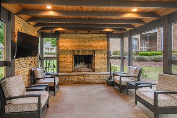 A patio with a fireplace and chairs at Ashford Place Apartment Homes, Flowood, 39232
