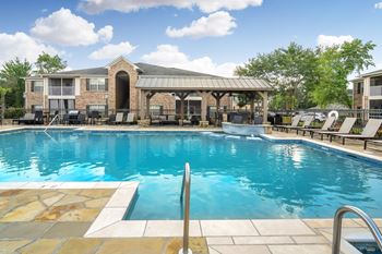 A large swimming pool with a patio and lounge chairs at Ashford Place Apartment Homes, Flowood, 39232