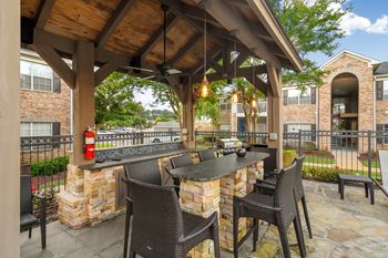 A patio with a table and chairs under a wooden roof at Ashford Place Apartment Homes, Flowood