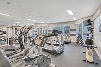 A gym with treadmills, elliptical machines, and other exercise equipment at Ashford Place Apartment Homes, Flowood, MS