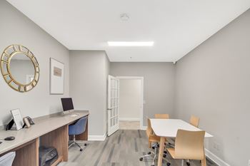 A room with a desk, chairs, and a round mirror on the wall at Ashford Place Apartment Homes, Flowood, MS 39232