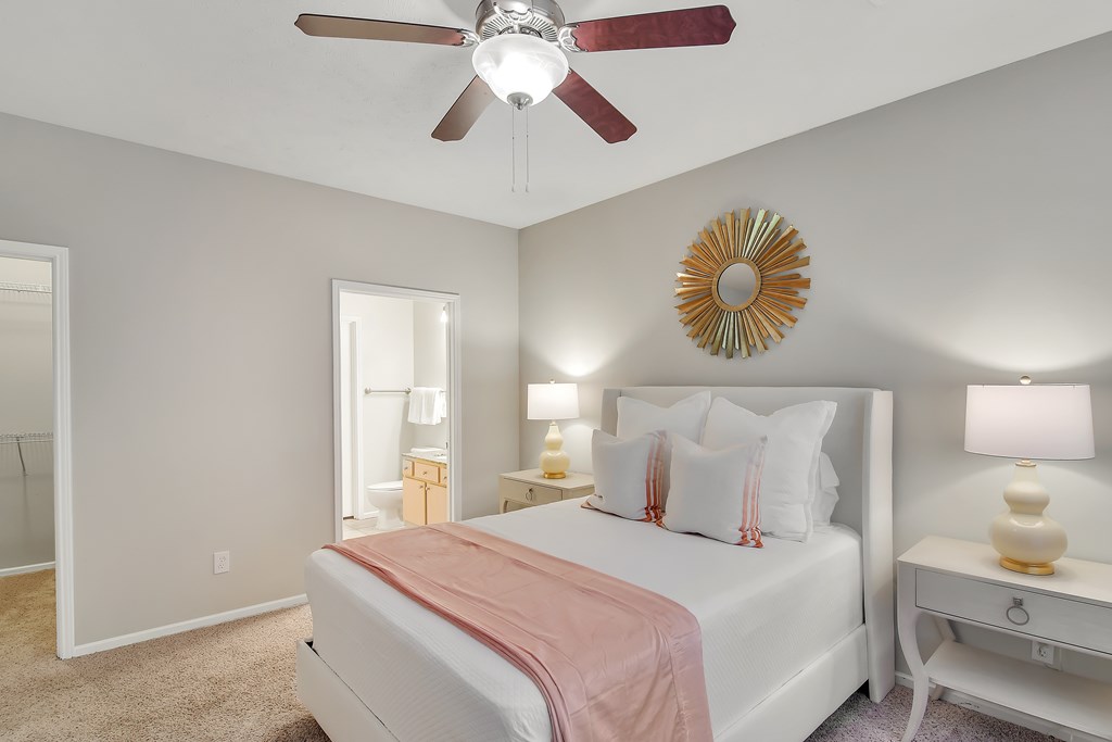 A bedroom with a bed, nightstands, and a ceiling fan at Ashford Place Apartments, Flowood, MS 39232
