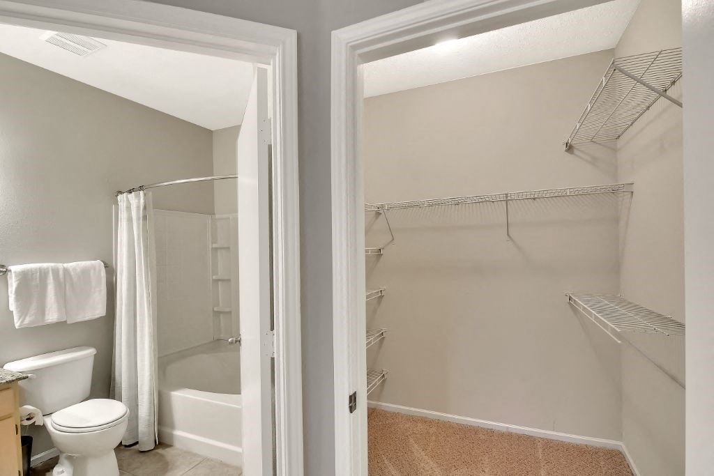 a bathroom with a white toilet next to a white bathtub at Ashford Place Apartment Homes, Flowood, MS