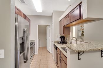 A kitchen with a refrigerator, sink, and cabinets at Ashford Place Apartment Homes, Mississippi 39232