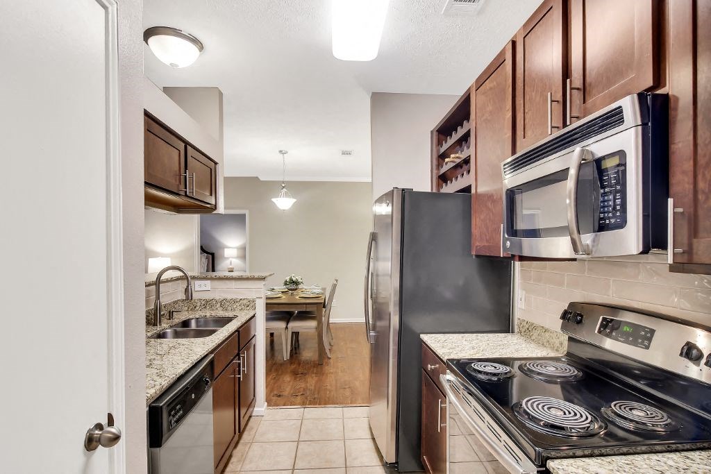 a kitchen with wooden cabinets and stainless steel appliances at Ashford Place Apartment Homes, Flowood
