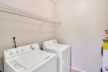 A white washing machine and dryer in a laundry room at Ashford Place Apartment Homes, Flowood, MS 39232
