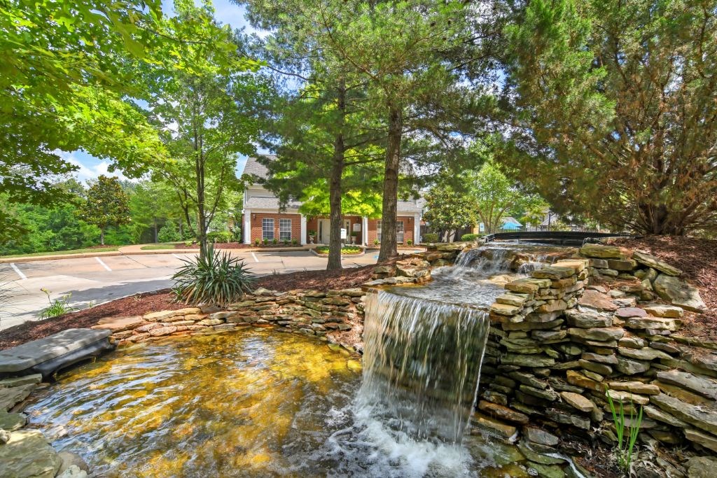 a waterfall in a park with a building in the background  at Legacy Apartment Homes, Ridgeland, 39157