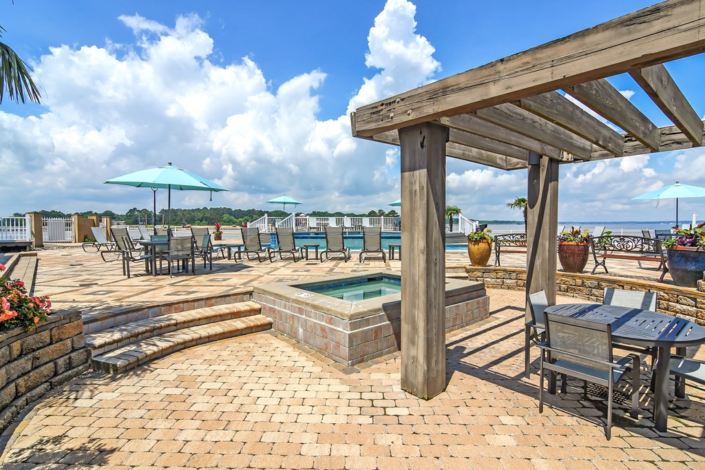 the patio has a hot tub and tables with umbrellas at Lakeshore Pointe Apartment Homes, Brandon, MS, 39047