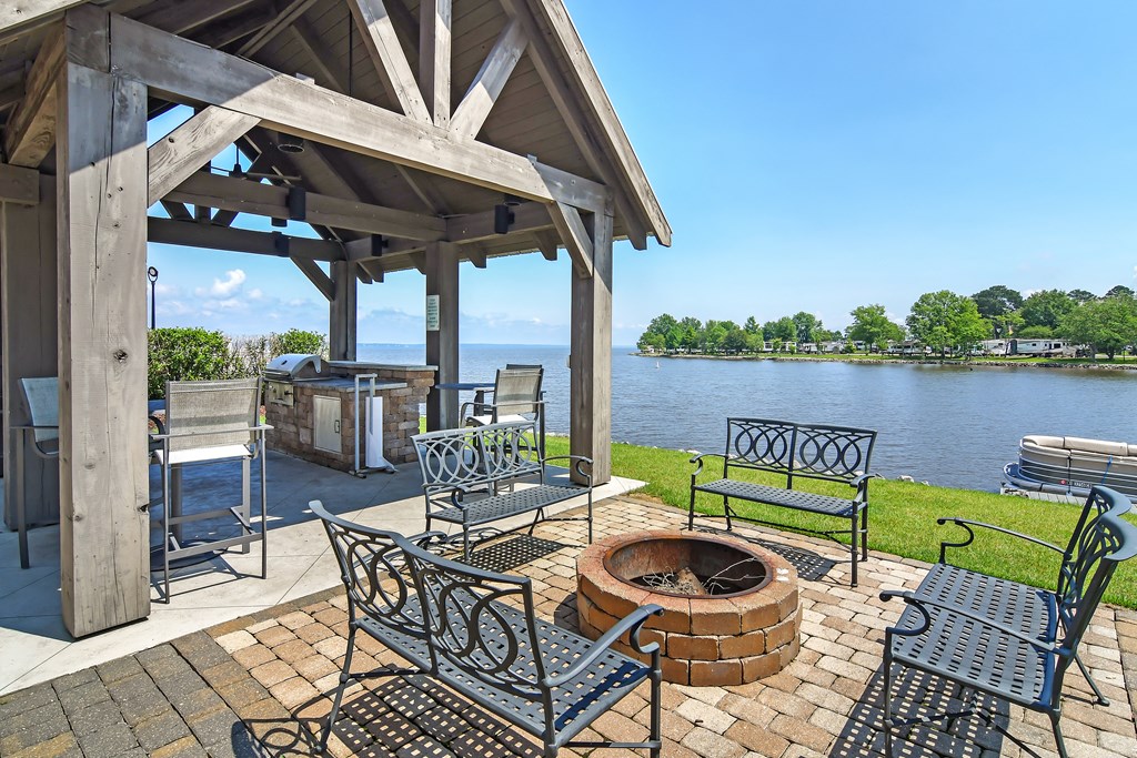 a patio with a fire pit and chairs next to a lake at Lakeshore Pointe Apartment Homes, Brandon, MS