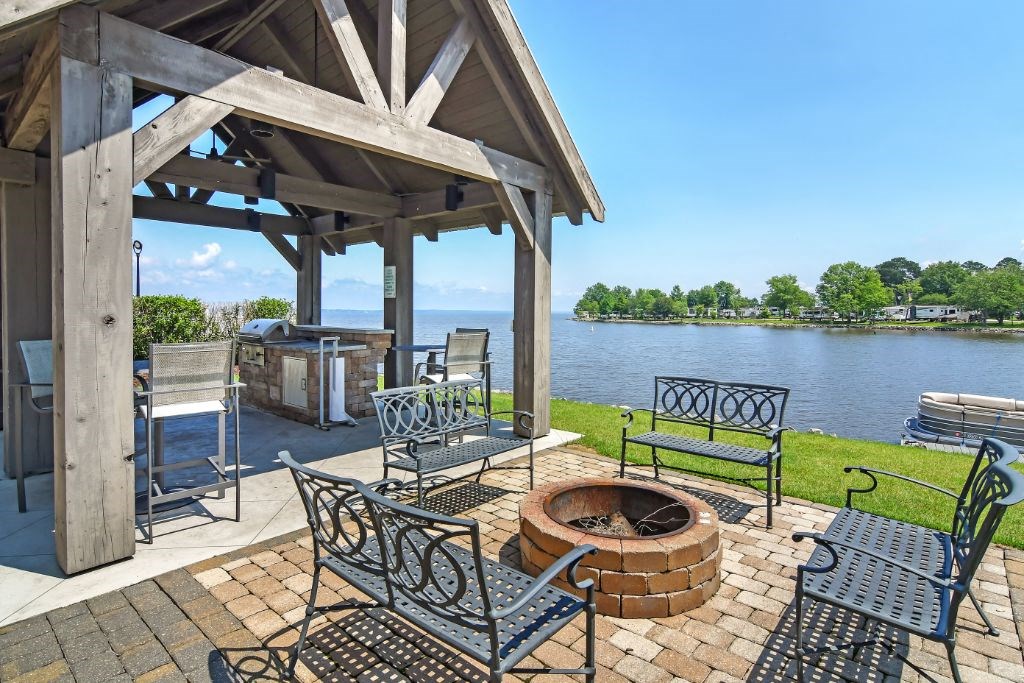 a patio with a fire pit and a grill next to a body of water at Lakeshore Pointe Apartment Homes, Mississippi