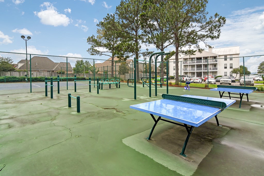 a tennis court at a park with ping pong tables at Lakeshore Pointe Apartment Homes, Brandon, MS