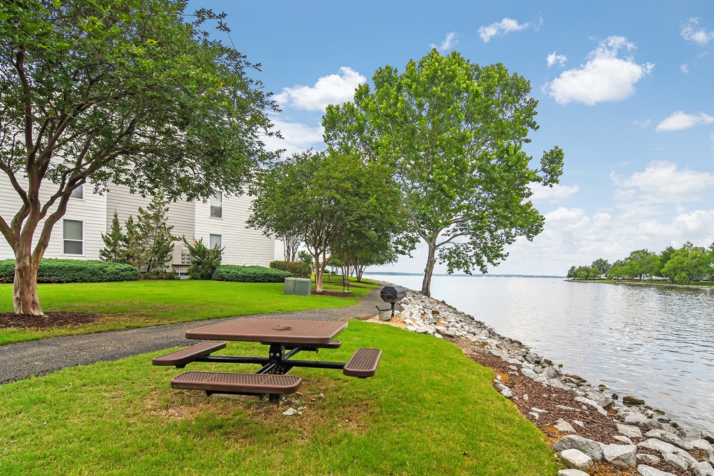 a picnic table on the grass next to the water at Lakeshore Pointe Apartment Homes, Brandon, 39047