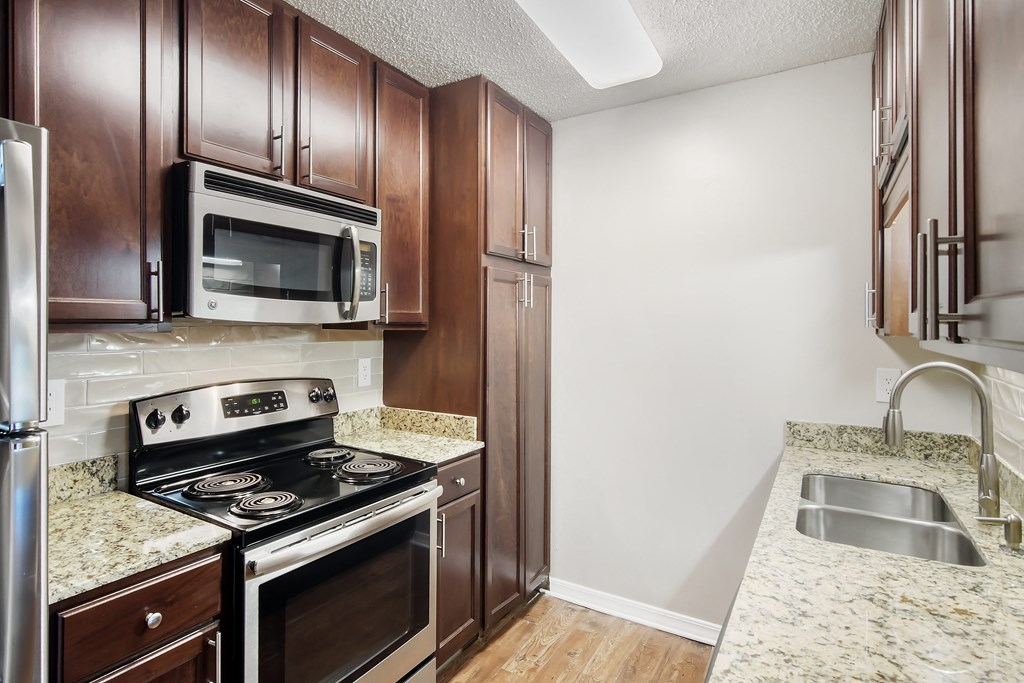 a kitchen with wood cabinets and stainless steel appliances and granite counter tops at Lakeshore Pointe Apartment Homes, Brandon, 39047