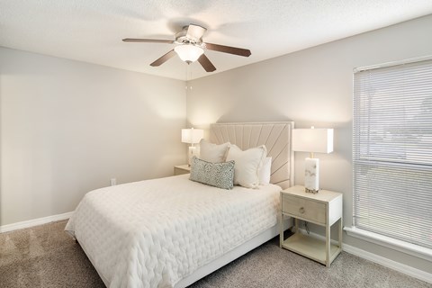 A bedroom with a bed, nightstand, and a ceiling fan.