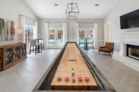a long shuffleboard table in the middle of a living room with a fireplace at Bridgewater Apartment Homes, Brandon, MS