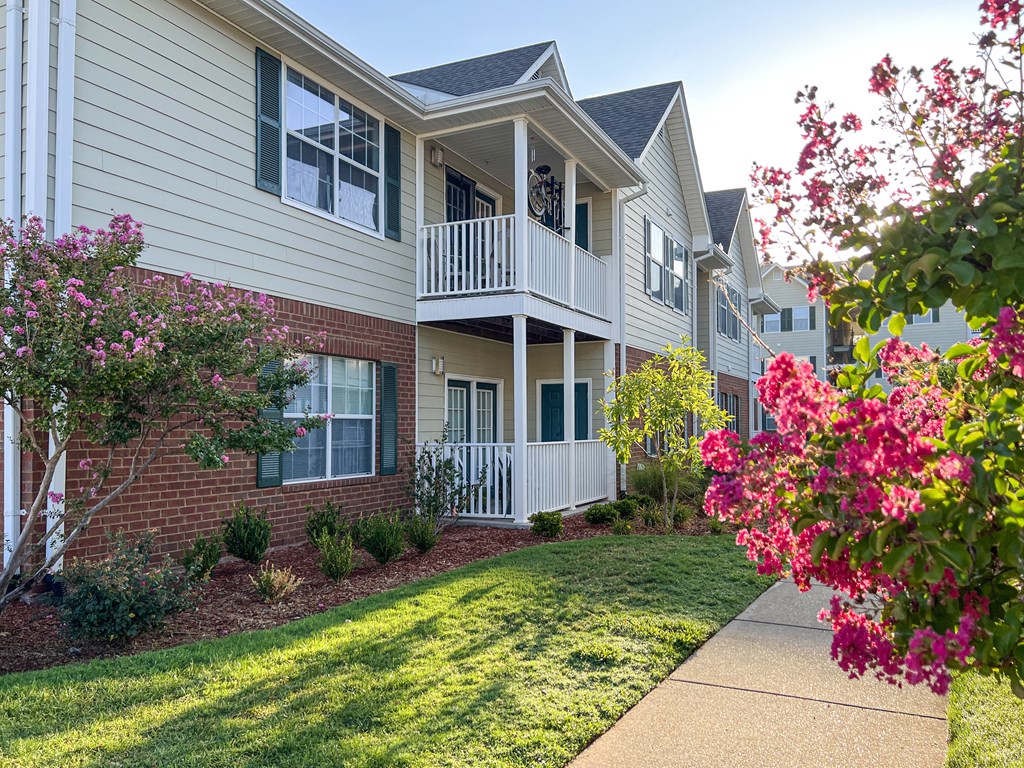an exterior view of an apartment building with a lawn and flowers at The Madison Apartment Homes in Tyler, TX 