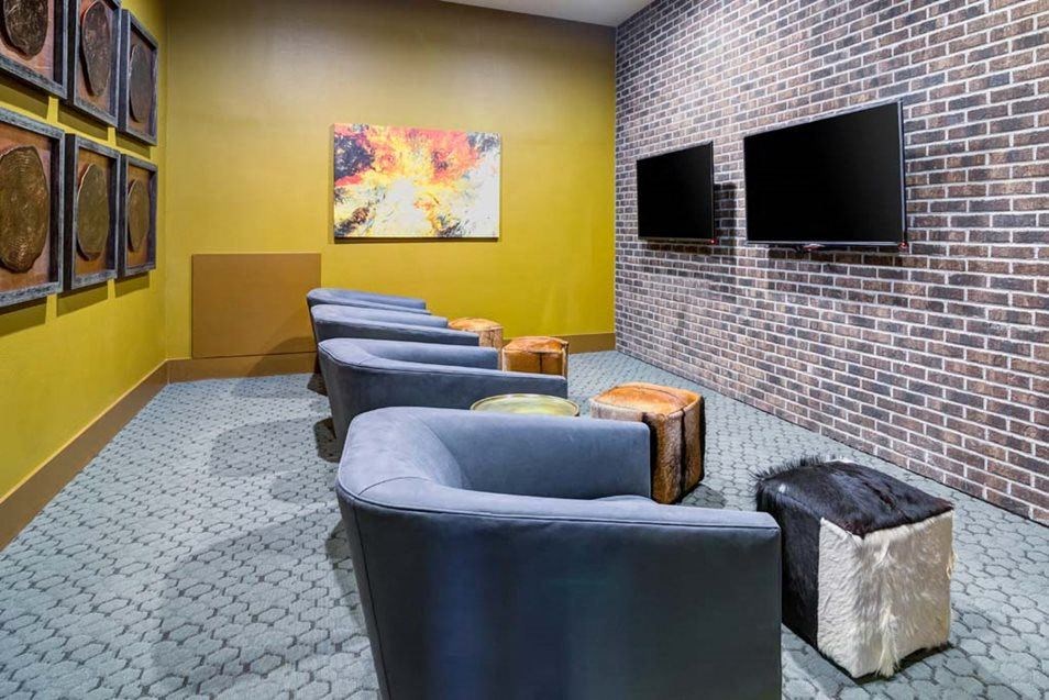 a waiting room with blue chairs and a brick wall at The Retreat Apartment Homes in Williston, 58801