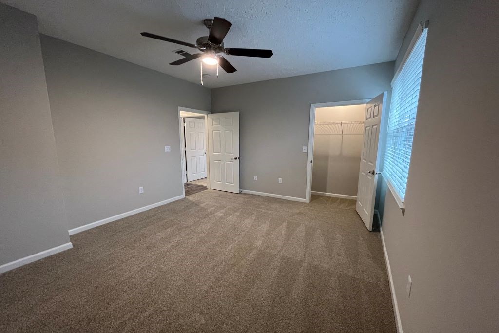 an empty living room with a ceiling fan and a door at Carlton Park Apartment Homes, Flowood, Mississippi, 39232
