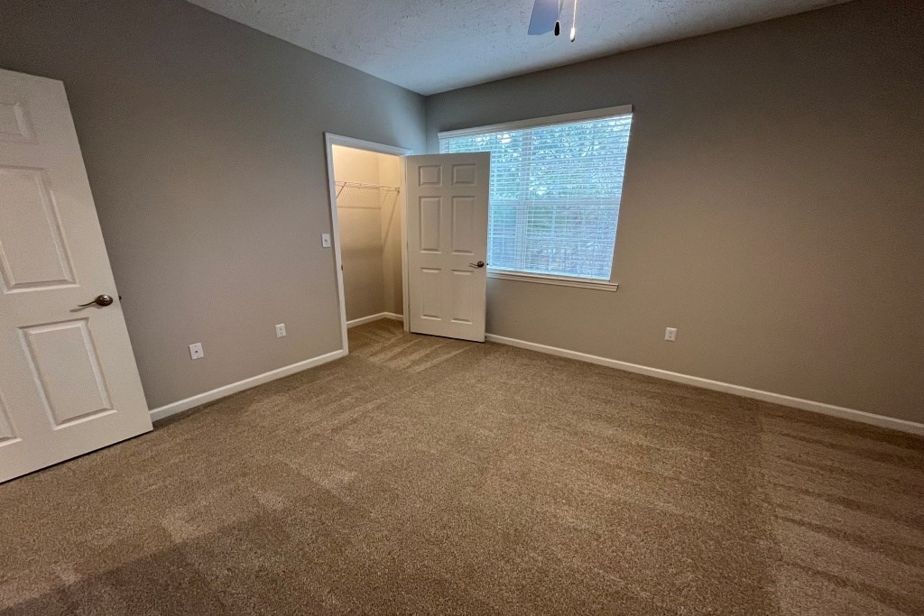 an empty living room with carpet and a window at Carlton Park Apartment Homes, Flowood, MS, 39232