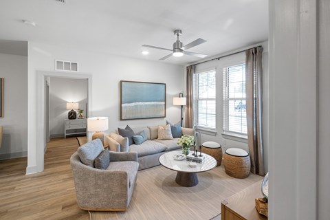 A modern living room with a grey couch, a coffee table, and a painting on the wall at Saltaire Apartment Homes in Santa Rosa Beach, FL